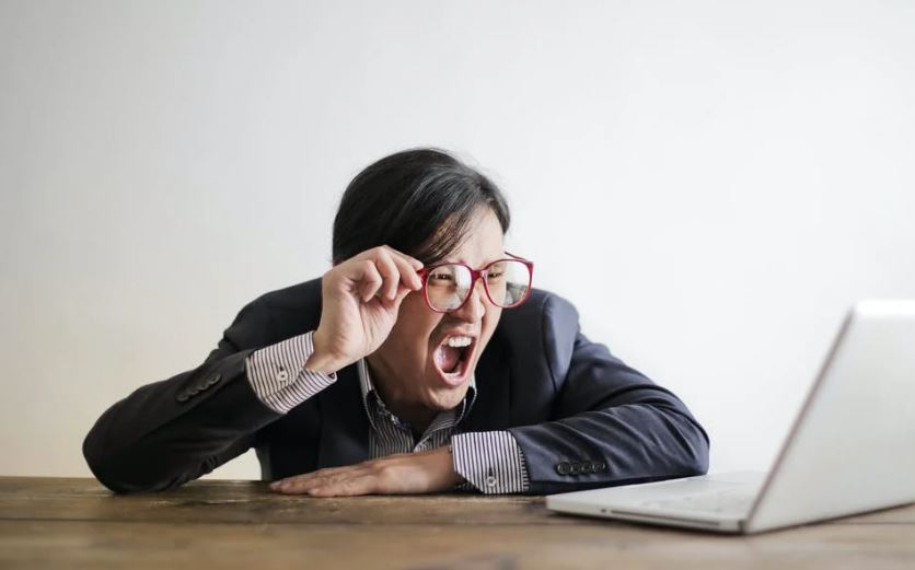 Homem gritando no computador por causa de overposting